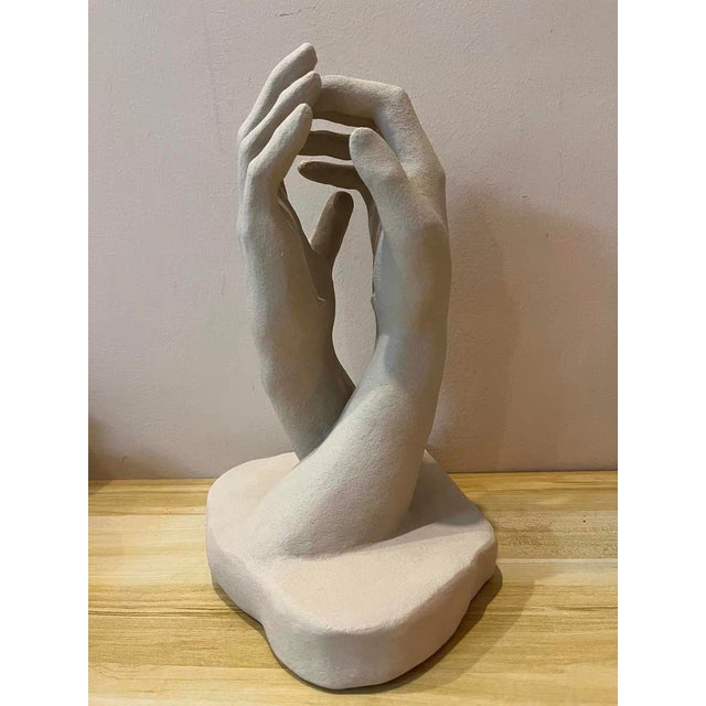 Centered around a hand gesture, this piece is made of cement with a matte light gray finish. A small candle holder rests...