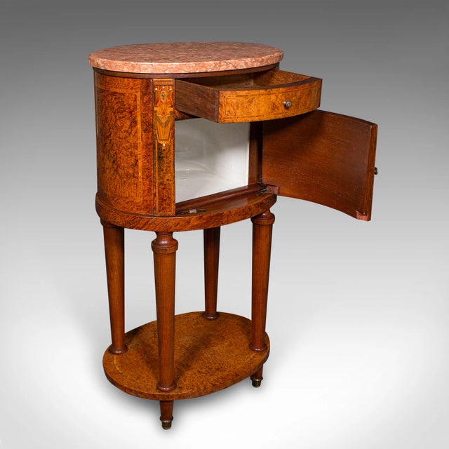 This is an antique oval bedside cabinet. A French, Amboyna and marble boudoir or bathroom nightstand, dating to the...