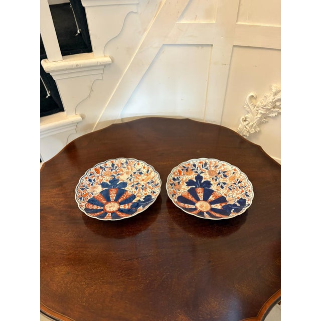 A charming pair of scalloped-edge Japanese Imari plates decorated in the traditional palette of underglaze cobalt blue and...