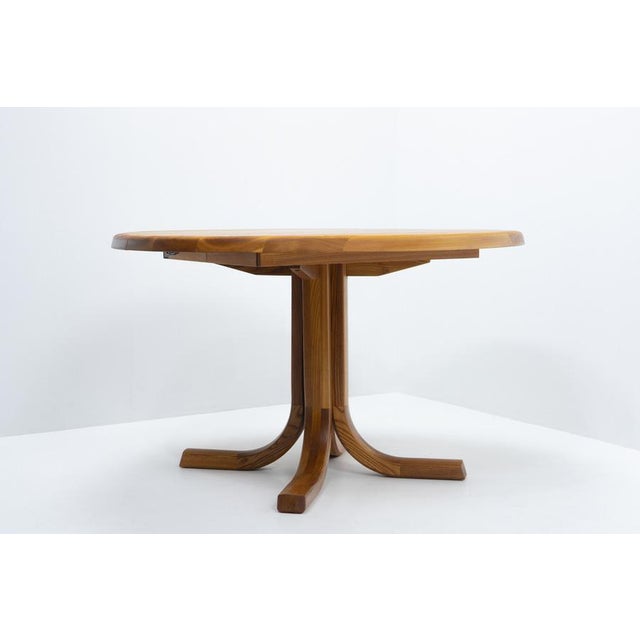 Round extendable dining table by Ebenisterie Seltz, produced in the 1980s in France, crafted in solid European elm. The...