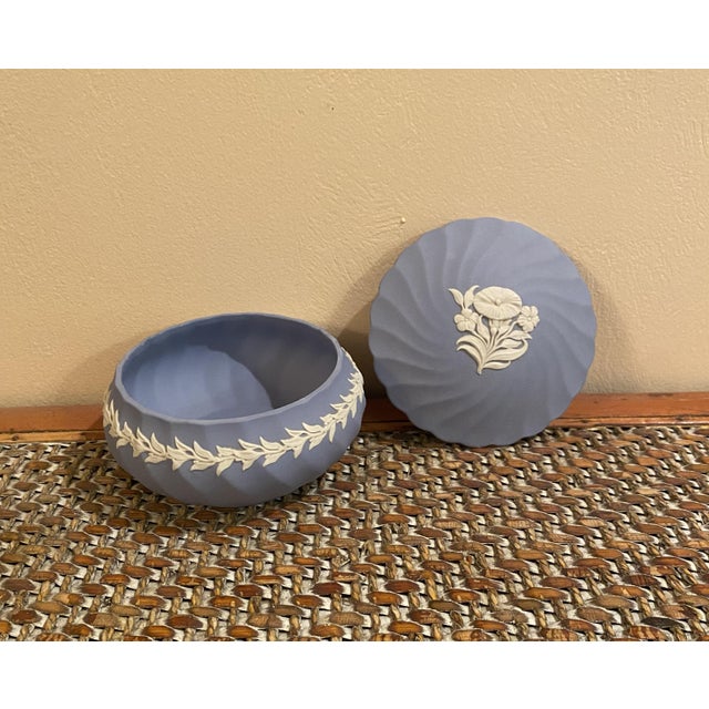 Beautiful Wedgwood lidded round box with scalloped edges. White decorative trim around the the box with white pansies on...