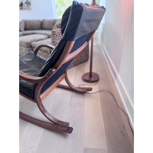 Mid-century modern vintage rocking chair with sculpted bentwood frame and black padded leather seat and headrest....