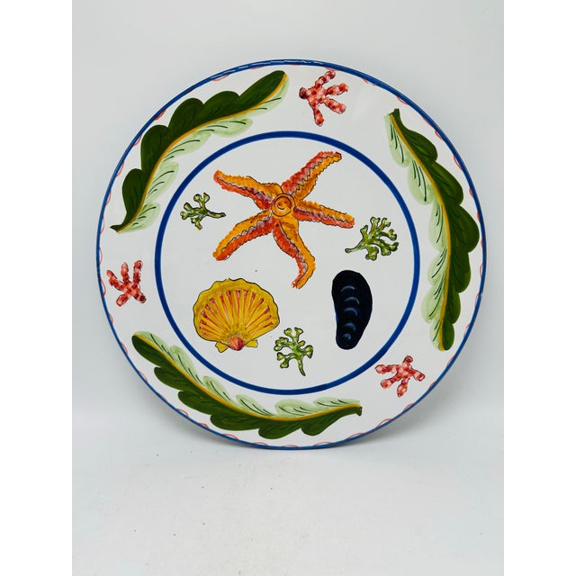 This is a hand-painted Italian ceramic cake plate with a bright coastal motif. The front features a lively marine design:...