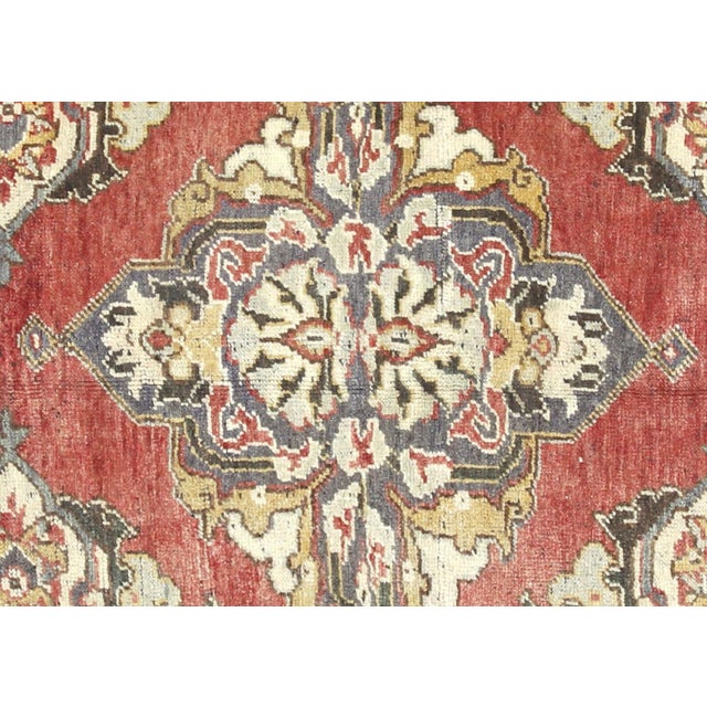 This vintage Turkish Oushak rug, measuring 4'8" by 11'6", is handwoven with wool on a wool foundation in the Oushak region...