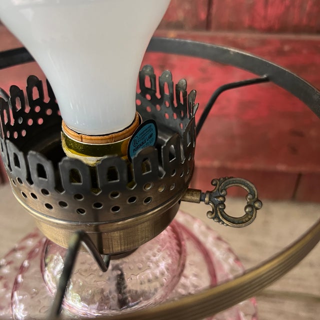 This vintage lamp set features pink hobnail glass bases paired with ornate metal stands, blending antique charm with...