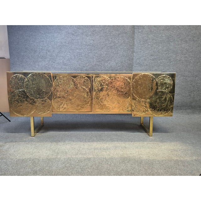A brass sideboard inspired by the moon enchants with its chiseled surface, rich with craters and curves that evoke the...