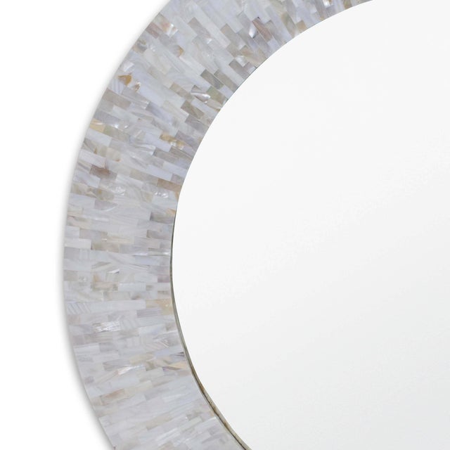 Ivory mother of pearl edges surround this round modern mirror, lending a touch of subtle iridescence and natural beauty....
