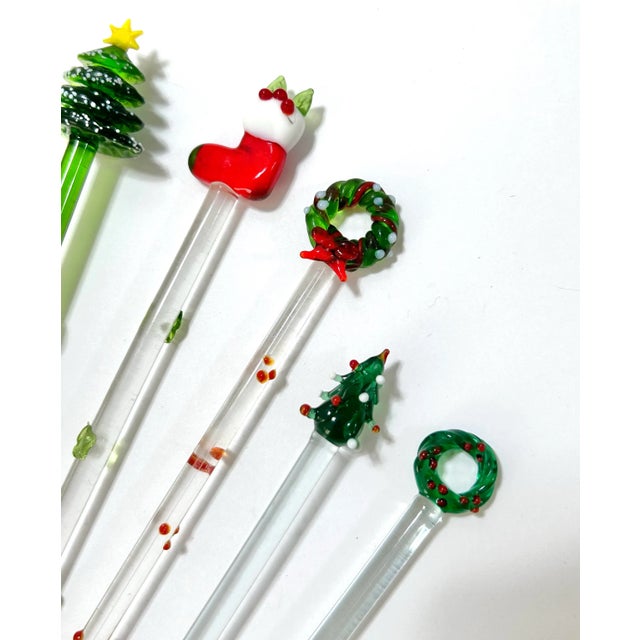 A festive collection of vintage Murano-style art glass swizzle sticks featuring whimsical sculptural motifs including...