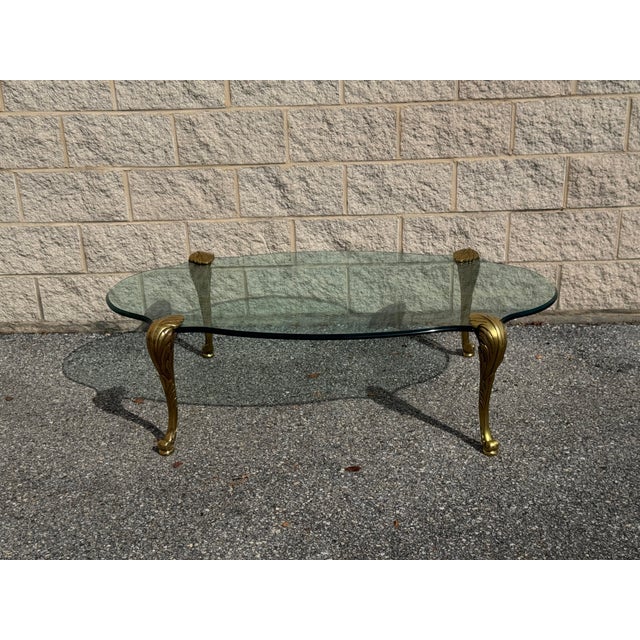 Vintage coffee table featuring a generously proportioned clear glass top with a softly undulating silhouette, supported by...