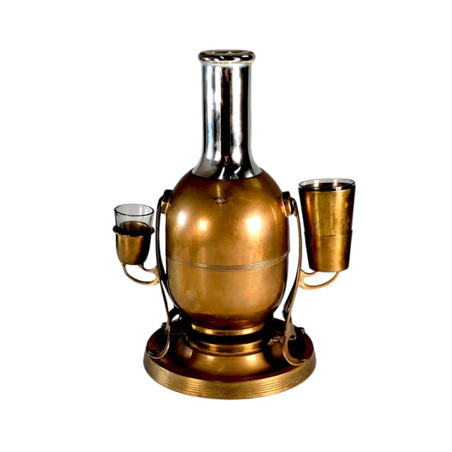 This thermos is made of brass and glass lined. It is seated on a hinged base and pourer. each side contains two cups one...