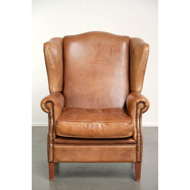 This lovely and comfortable English-style wing armchair is made of sheepskin and has a beautiful light cognac color. It...
