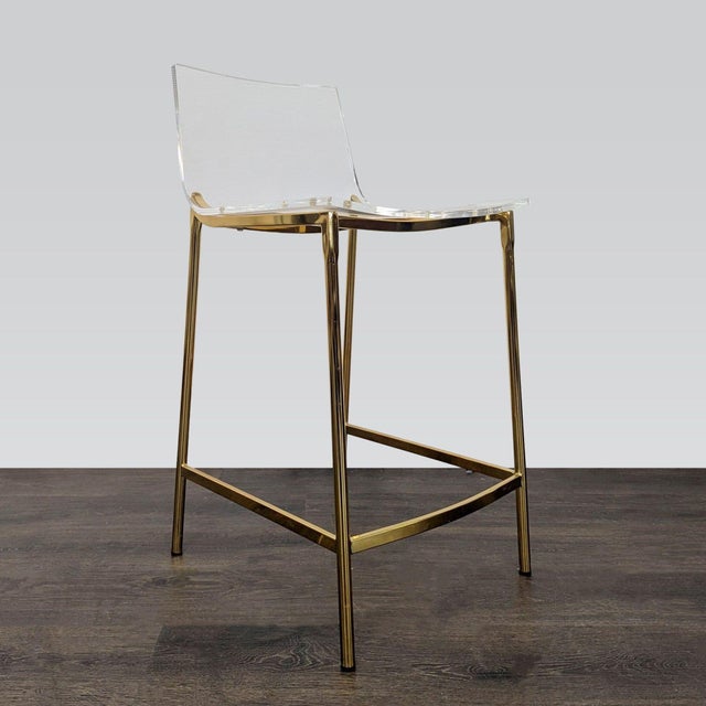 Clear acrylic stool with gold legs. Brand: CB2. Original Price: $299. Dimensions (in): 18W x 16D x 34H.