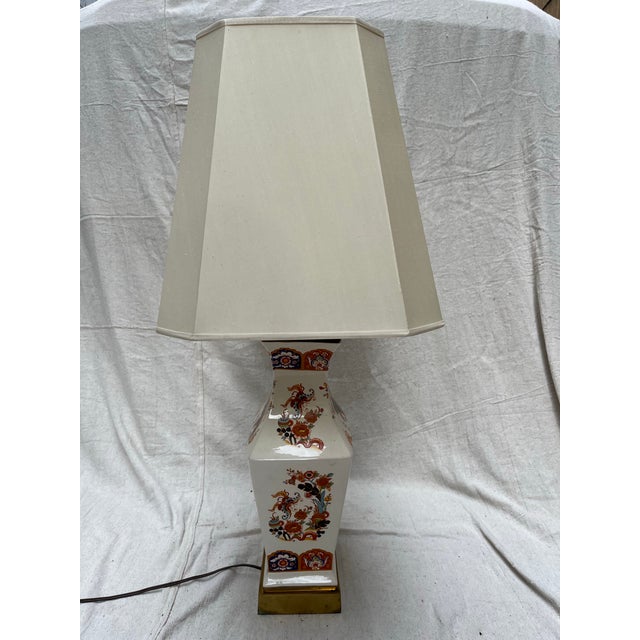 A single vintage baluster form porcelain lamp with traditional Imari style gilt decoration. Includes hard back lamp shade....