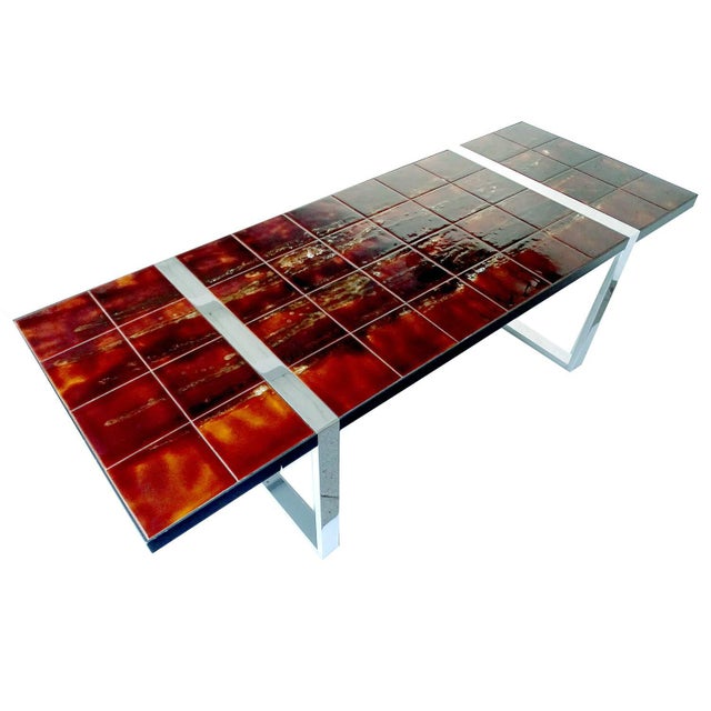Large mid-century table featuring ceramic tiles supported by a chrome frame. The tiles were produced in flamed hues...