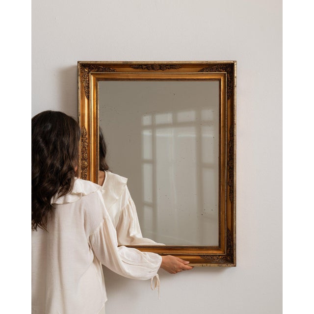 Carved giltwood mirror in Antique Gold. Its antique gold finish sets off rectangular molded gilt frame, warm patina, a...