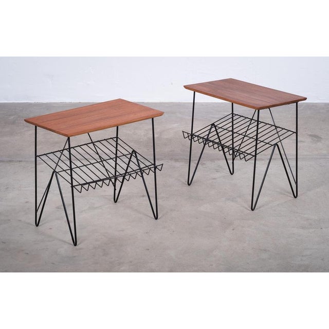Charming pair of Danish side tables from the 1960s, crafted with teak tops, integrated magazine racks, and elegant metal...