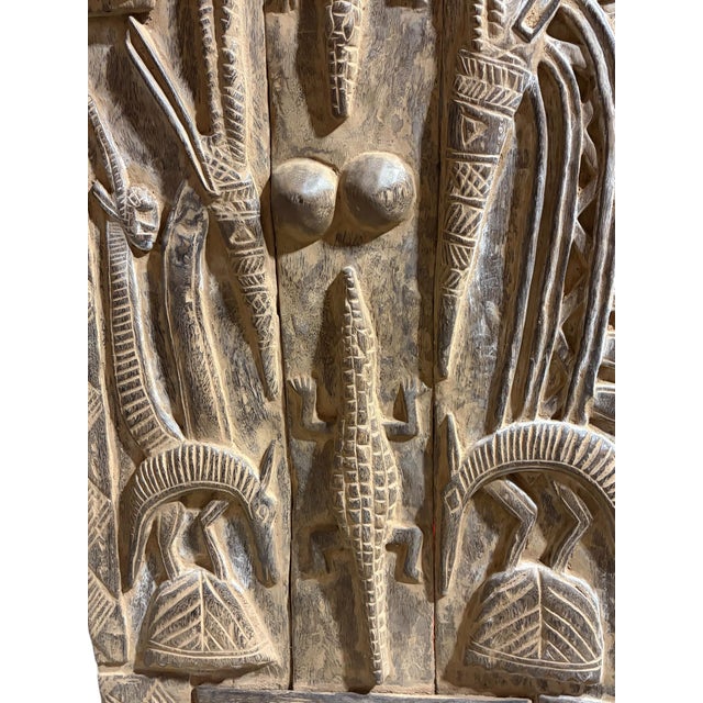 This vintage Dogon granary door from Mali showcases exceptional carved relief artistry, featuring four standing chiwaras...