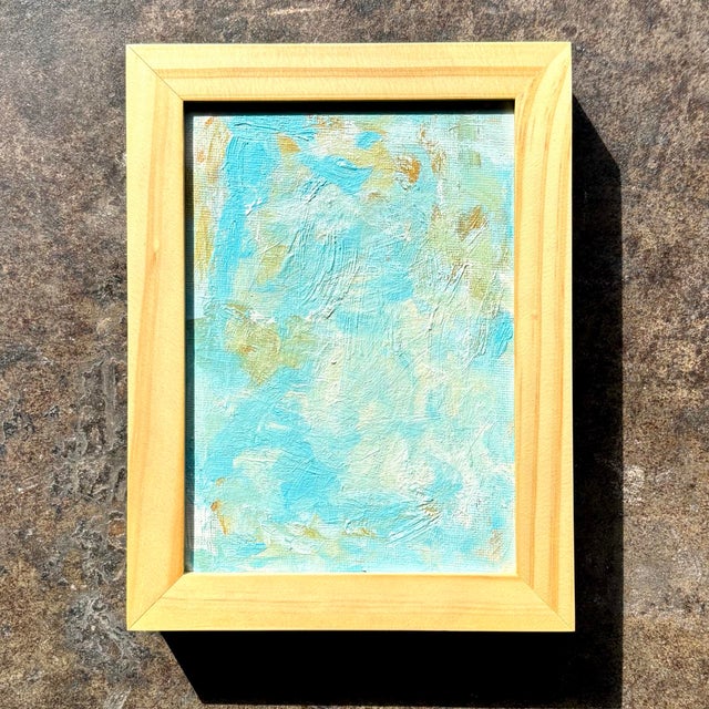 This small abstract painting features soft, layered strokes of turquoise, aqua, and pale sea-green, with subtle hints of...