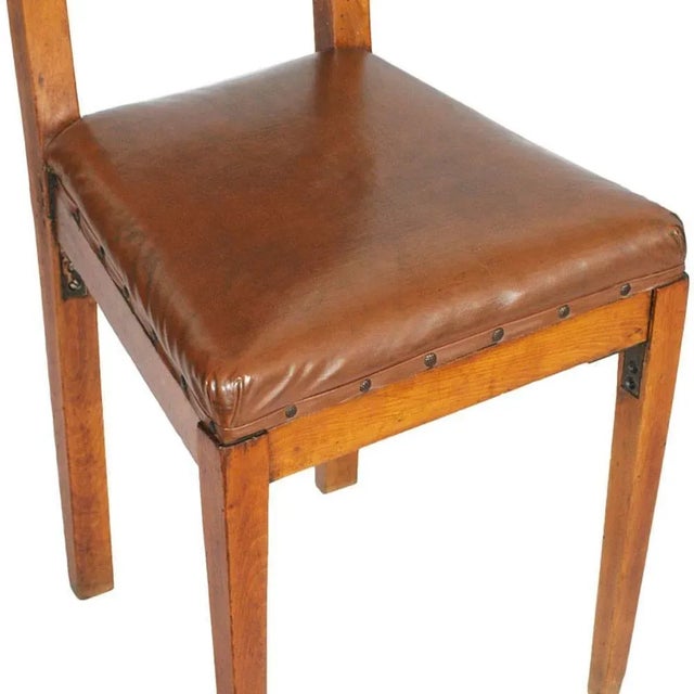 This early 20th-century Art Nouveau pair of chairs is carved from solid cherry wood and upholstered in leather.