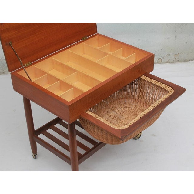 Vintage 1960s sewing storage cabinet. Made of teak. with a hinged lid and a light-colored veneer interior. Includes a...