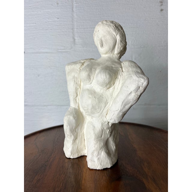 An expressive and tactile hand-built plaster sculpture depicting a stylized female form. This piece celebrates the "divine...