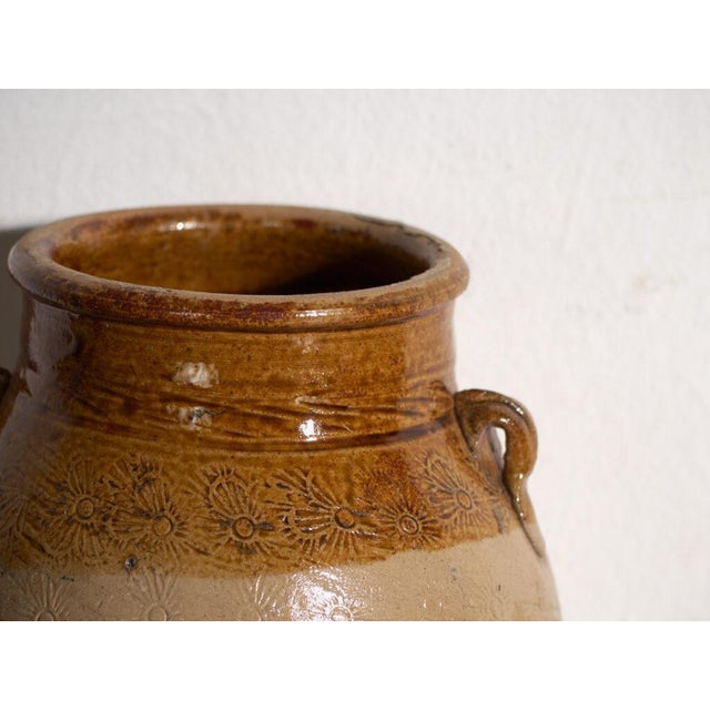 This antique Chinese glazed stoneware vase is an ovoid jar with a caramel glaze with lug handles and stamped decoration of...