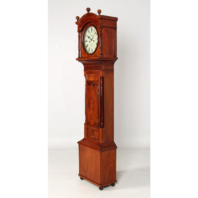 Antique English grandfather clock with painted dial in mahogany case The case stands on small round feet and has a wide...