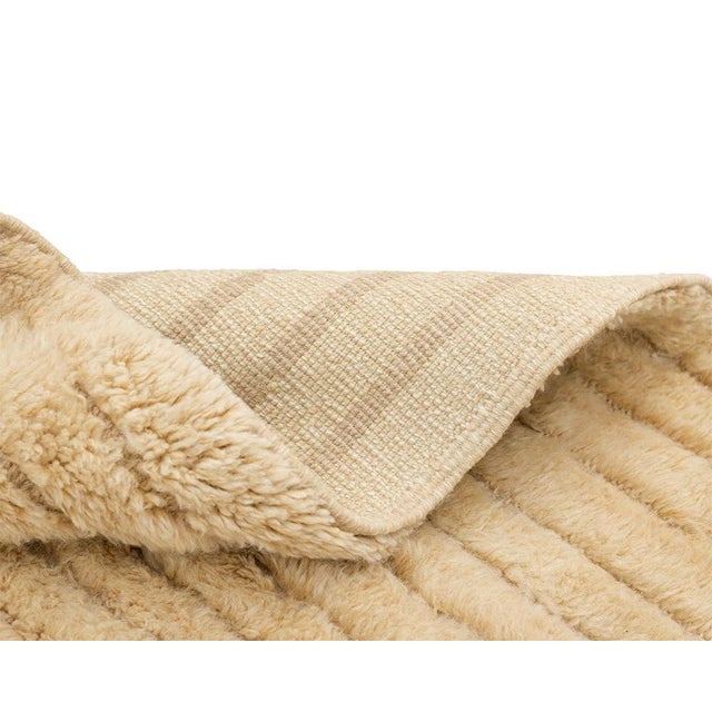 Textural hand-knotted wool rug in rich Fawn, featuring a rhythmic vertical ribbed pattern that enhances its tactile...