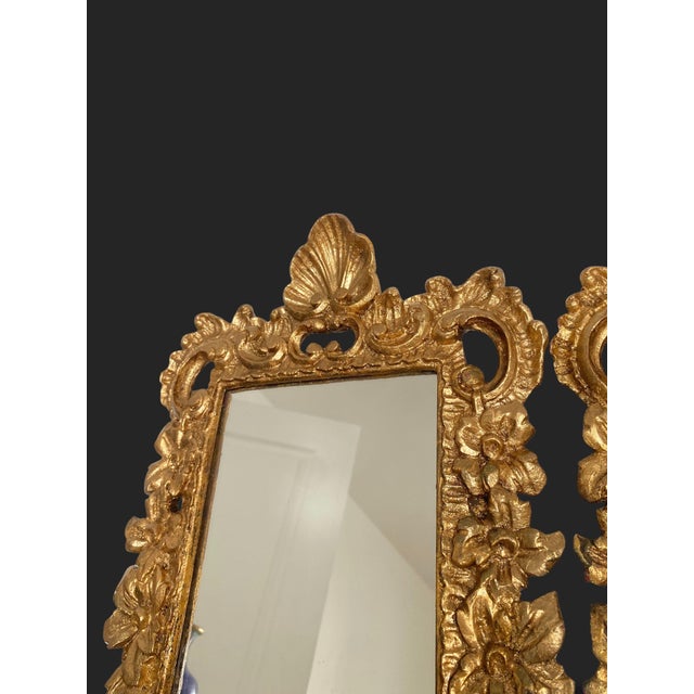Pair of small rectangular mirrors in carved and gilded wood, richly decorated with foliage, rocaille scrolls, and a shell...
