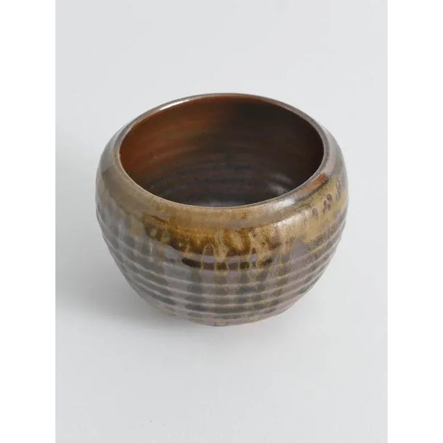 This hand-thrown stoneware bowl features the distinctive ribbed pattern, gracefully finished with a charming spiral motif...