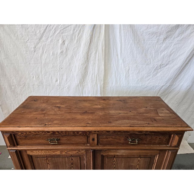 Late 19th-century European provincial sideboard or farmhouse cabinet crafted from richly grained solid pine. This rustic...