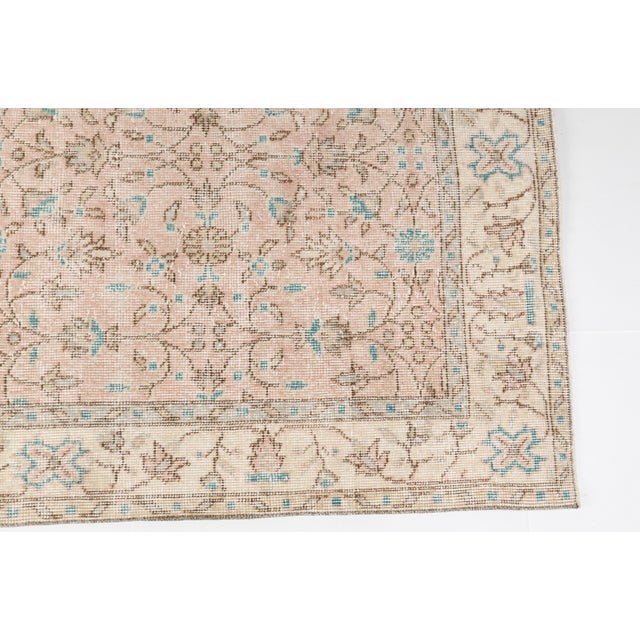 This is a vintage Turkish Oushak rug from the Mid 20th Century. The piece was hand-knotted.