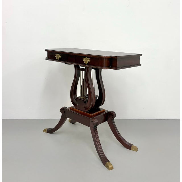 A vintage Regency-style side table crafted in a rich mahogany finish, featuring a rectangular top with softly rounded...