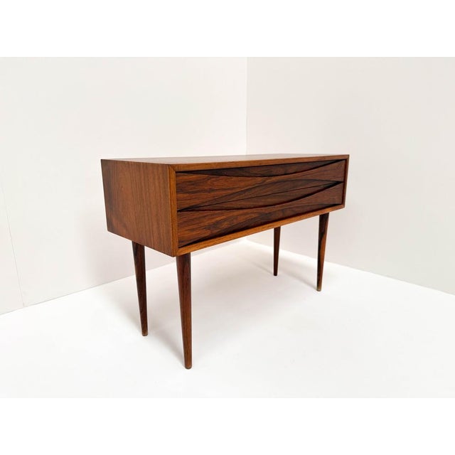 Add a touch of Danish mid-century modern elegance to your home with this stunning rosewood bedside chest, designed by...