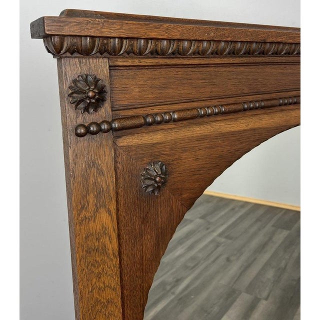 A beautifully crafted Vintage French oak mirror featuring an elegant oval mirror plate, decorative carved floral motifs...