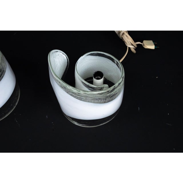 Elegant and sculptural, these lamps feature thick, curved white Murano glass shades with a smooth, flowing silhouette. The...