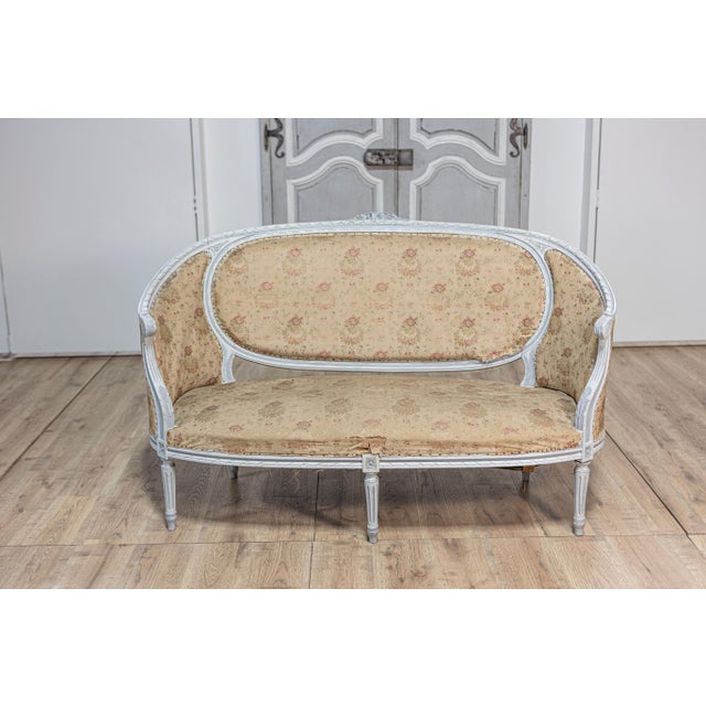 A French Louis XVI style sofa from circa 1900 with soft light blue painted finish, carved floral motif on the crest,...