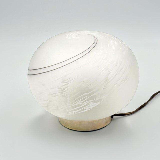 Sculptural Murano glass table lamp produced in Italy during the 1980s. The design combines a softly rounded oval diffuser...