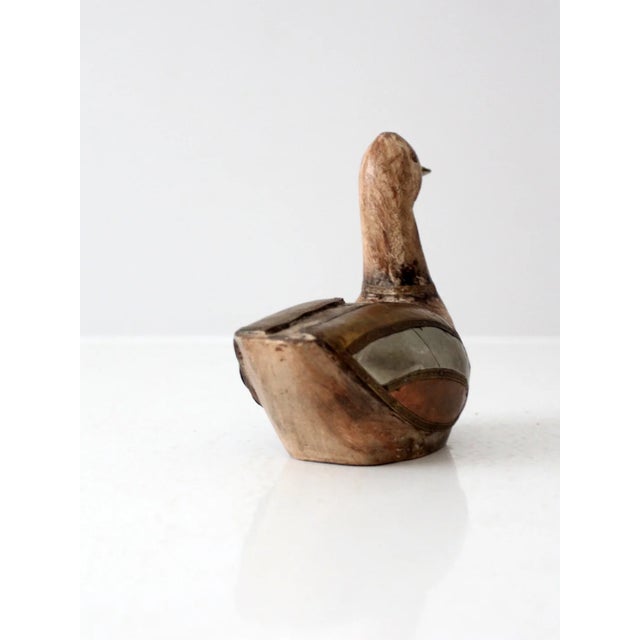 This is a vintage wood & metal duck sculpture. The folk art wooden figurine features brass, copper, and silver tone accents.