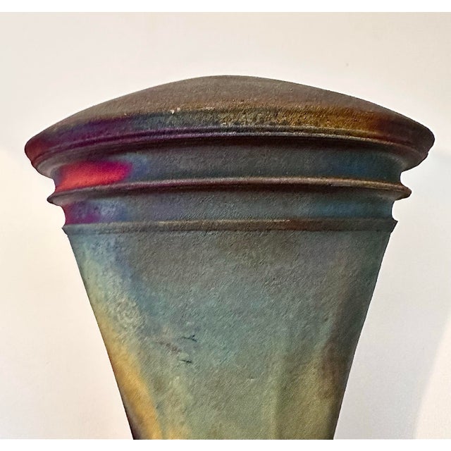 This handcrafted raku‑style ceramic vessel features a flared trumpet form with a narrow base, wide rim and mouth opening...
