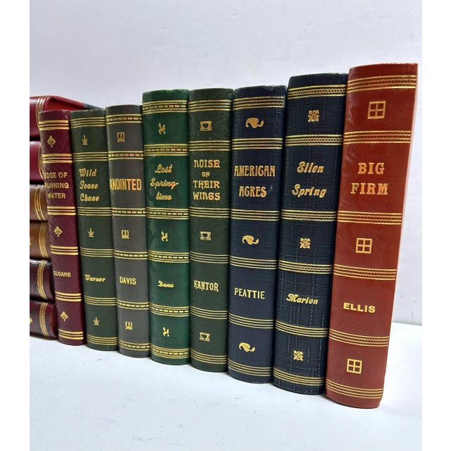 A curated collection of 14 antique decorative books in rich red, blue, green, and brown bindings with gilt lettering,...