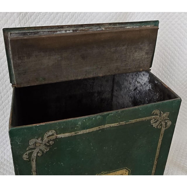 This 19th century painted metal box features a rich, deep green ground accented with hand-applied gilt borders and...