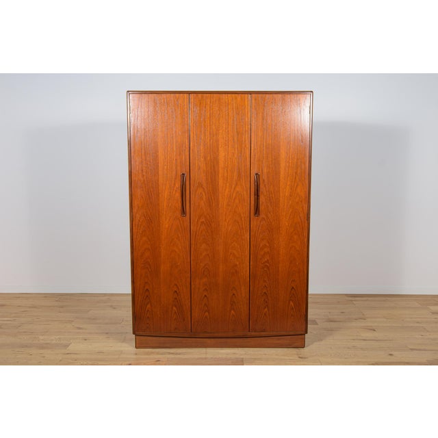 This mid century wardrobe in teak was produced in United Knigdom by G Plan in the 1960s. Wardrobe with three doors, inside...