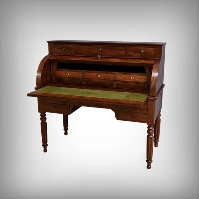 This Restoration period roll-top desk is crafted from solid mahogany and mahogany veneer. It opens at the top with a shelf...