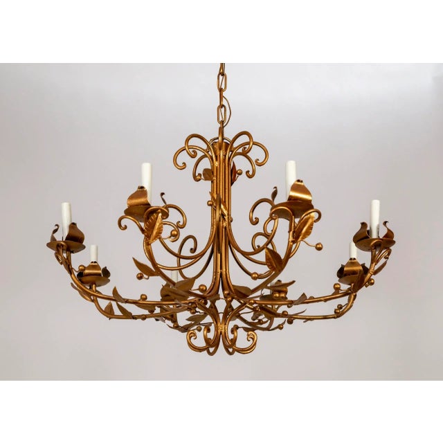 A metal chandelier painted rose gold with curving arms adorned with subtle, simple leaves and berry shapes. Newly rewired....