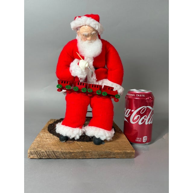 Charming vintage American folk art Christmas sculpture depicting Santa Claus as a traditional toymaker, seated in his...