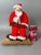Charming vintage American folk art Christmas sculpture depicting Santa Claus as a traditional toymaker, seated in his...