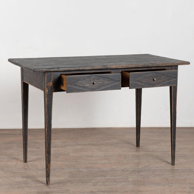 19th century Swedish side table crafted in pine. The table features two drawers carved with traditional fluted diamond...