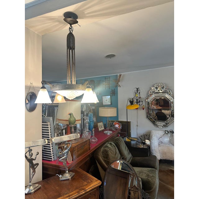 Magnificent Art Deco chandelier in wrought iron and polished glass typical of the 1930s. The wrought iron structure is...