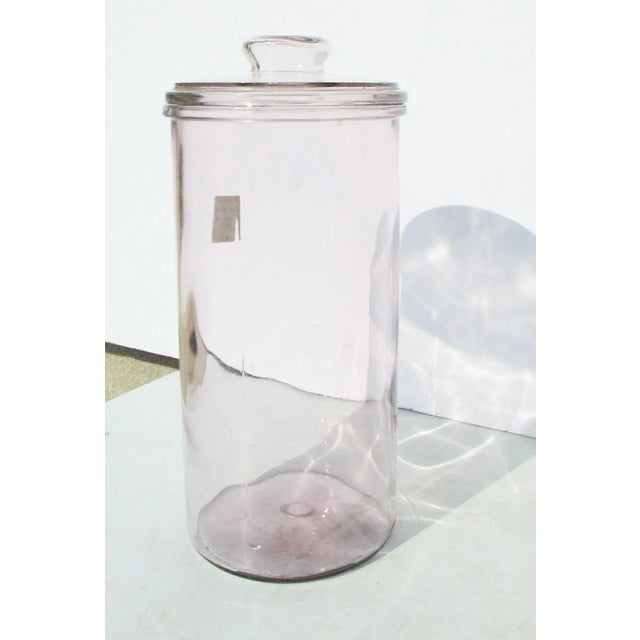 Tall lidded cylinder jar. Vintage early 20th-century hand-made or hand-rolled with a manganese glass now showing the...